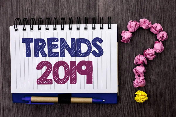 Rukopis textu trendy 2019. Pojetí znamená současné hnutí nejnovější značky nové koncepce predikce napsané na Notebook kniha o dřevěné pozadí pero a otazník vedle ní. — Stock fotografie