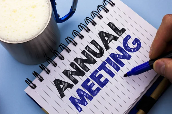 Conceptual hand writing showing Annual Meeting. Business photo text Yearly Company Assembly Business Conference Report Event written by Man on Notebook Book Holding Marker plain background Cup.