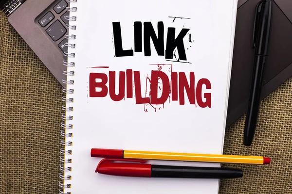 Writing note showing  Link Building. Business photo showcasing Process of acquiring hyperlinks from other websites Connection written on Notebook Book placed on Laptop with jute background Pens