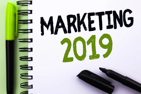 Signo de texto que muestra Marketing 2019. Foto conceptual Estrategias de mercado de Año Nuevo Nuevo Nuevo comienzo Ideas publicitarias escritas en el cuaderno Libro sobre el fondo verde Marcador y pluma al lado . — Foto de Stock