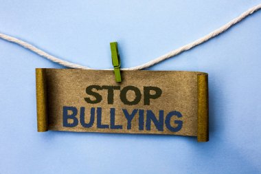El yazısı metin durdurmak zorbalık. Kavram anlam istismar taciz saldırganlık saldırı karton düz arka plan küçük ipte asılı kağıt üzerinde yazılı korkutuyor değil devam.