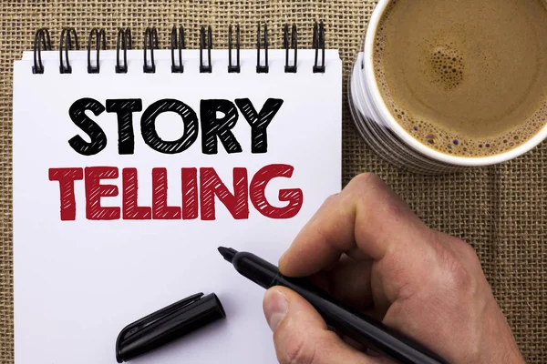 Text sign showing Story Telling. Conceptual photo Tell or write short Stories Share Personal Experiences written by Man Holding Marker on Notebook Book on the jute background Coffee Cup.