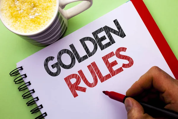 Word writing text Golden Rules. Business concept for Regulation Principles Core Purpose Plan Norm Policy Statement written by Man on Notebook Book Holding Marker on the plain background Coffee Cup