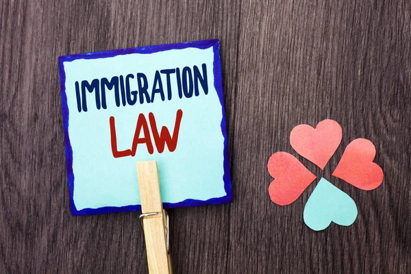 Handwriting text writing Immigration Law. Concept meaning National Regulations for immigrants Deportation rules written on Sticky Note Paper Holding With Clip on the wooden background Hearts.