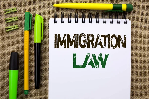 Γράφοντας κείμενο λέξη νομοθεσίας για τη μετανάστευση. Επιχειρηματική ιδέα για τους εθνικούς κανονισμούς για τους κανόνες απέλαση μεταναστών γραμμένο στο σημειωματάριο του βιβλίου για το φόντο της Γιούτα στυλό και συνδετήρες δίπλα. — Φωτογραφία Αρχείου