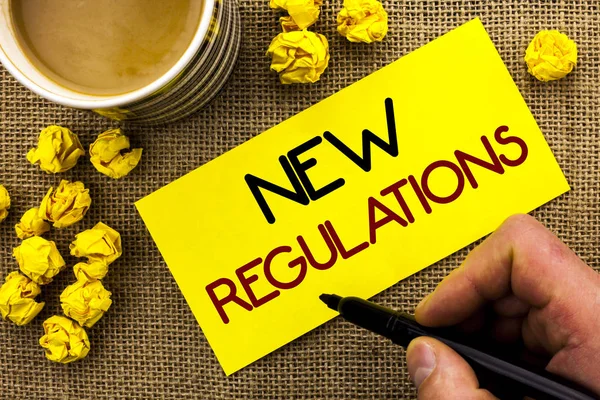 Text sign showing New Regulations. Conceptual photo Change of Laws Rules Corporate Standards Specifications written on Sticky Note Paper on the jute background Cup and Paper Balls next to it. — Stock Photo, Image