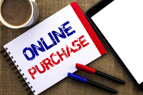 Handwriting text Online Purchase. Concept meaning Buy things on the net Go shopping without leaving home written on Notebook Book on the jute background Tablet Coffee Cup and Pens next to it.