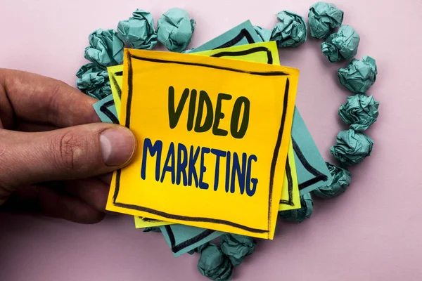 A kézírás szöveg Video Marketing. Koncepció, azaz média reklám multimédia promóciós digitális stratégia írta a Sticky Megjegyzés papír tartó ember tisztán látható háttér a szív papír golyó. — Stock Fotó