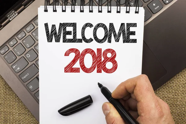 Word writing text Welcome 2018. Business concept for Celebration New Celebrate Future Wishes Gratifying Wish written by Man Holding Pen on Notebook Book placed on Laptop with jute background