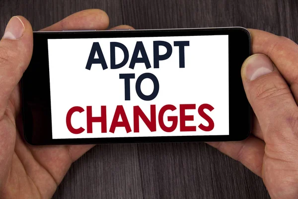 Writing note showing  Adapt To Changes. Business photo showcasing Innovative changes adaption with technological evolution written on Mobile Phone Screen holding by man on the wooden background. — Stock Photo, Image