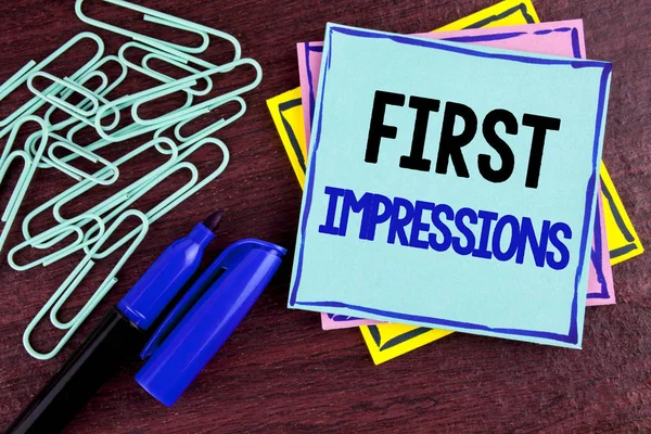 Handwriting text First Impressions. Concept meaning Encounter presentation performance job interview courtship written on Sticky Note Paper on wooden background Marker and Paper Clips next to it.