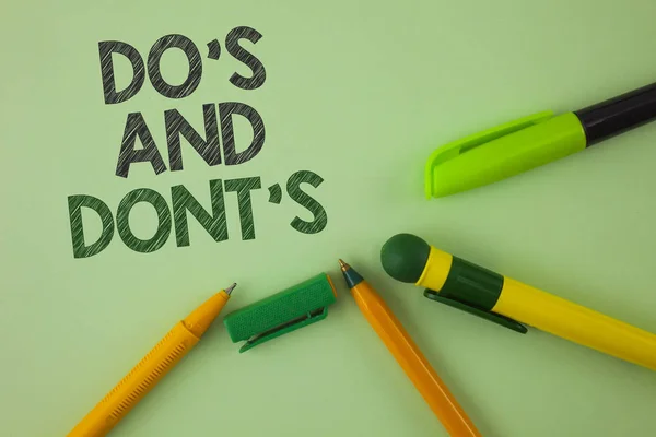 Handgeschreven tekst schrijven van do's en Don'Ts. Concept, wat betekent dat wat kan worden gedaan en wat kan niet weten rechts verkeerd geschreven op gewone groene achtergrond pennen ernaast. — Stockfoto