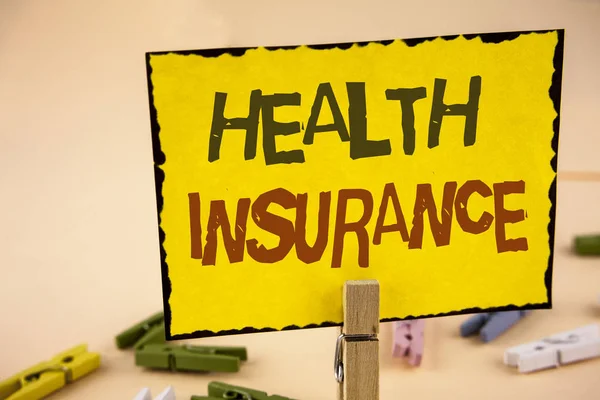 健康保険を書く手書き文字。概念意味健康保険の情報報道、医療サービス提供者、木製クリップの無地の背景に黄色粘着メモ紙に書かれました。. — ストック写真