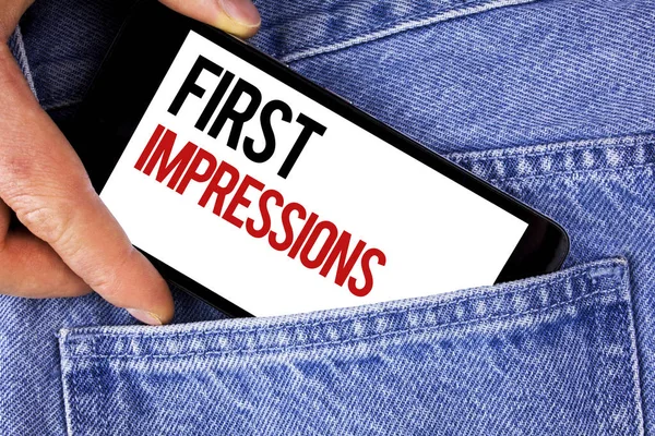 Text sign showing First Impressions. Conceptual photo Encounter presentation performance job interview courtship written on Mobile phone holding by man on the Blue Jeans background.