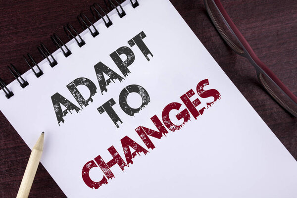 Text sign showing Adapt To Changes. Conceptual photo Innovative changes adaption with technological evolution written on Notepad on the Wooden background Pencil and Glasses next to it.