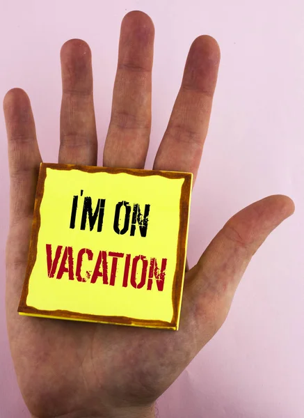 Textschild, das zeigt, dass ich im Urlaub bin. konzeptionelle Fotopause vom stressigen Arbeitsdruck weltweit auf gelbem, klebrigem Zettelpapier geschrieben, das auf der Hand auf dem schlichten Hintergrund liegt. — Stockfoto