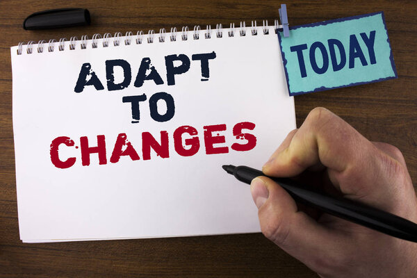 Handwriting text writing Adapt To Changes. Concept meaning Innovative changes adaption with technological evolution written by Man on Notepad holding Marker on wooden background Today Clip.