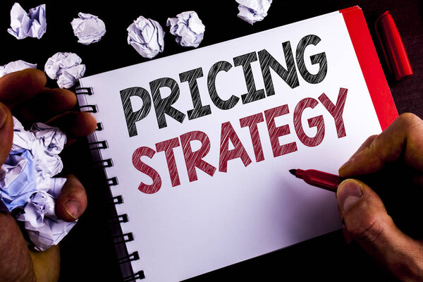 Writing note showing  Pricing Strategy. Business photo showcasing Marketing sales strategies profit promotion campaign written by Man on Notepad holding Marker wooden background Paper Balls