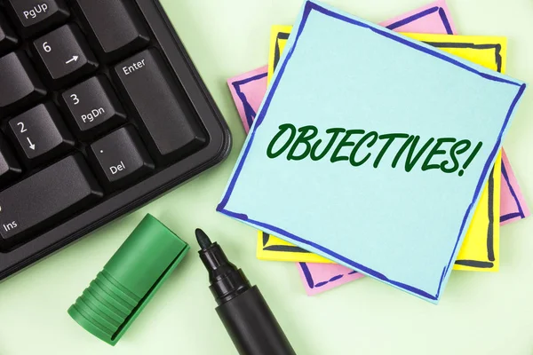 Handwriting text writing Objectives Motivational Call. Concept meaning Goals planned to be achieved Desired targets written on Sticky Note paper on plain Green background Marker and Keyboard. — Stock Photo, Image