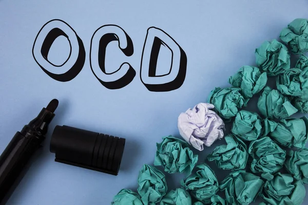 Tekst pisma Ocd. Koncepcję co oznacza obsesyjno-kompulsywne zaburzenia psychologiczne choroby stan chorobowy napisane na zwykłym niebieskim tle zmięty papier kulki i znacznik obok niego. — Zdjęcie stockowe