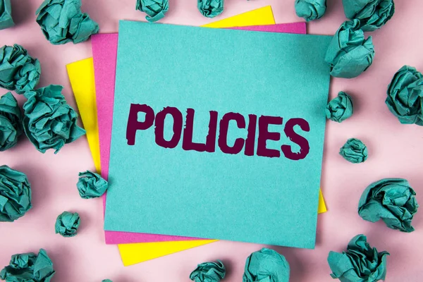 Handwriting text Policies. Concept meaning Business Company or Government Rules Regulations Standards written on Sticky Note Paper on plain background Crumpled Paper Balls next to it.