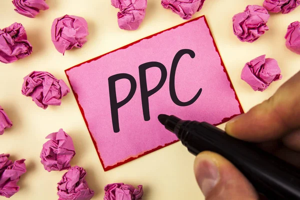 显示 Ppc 的文本符号. 按点击广告策略的概念性照片付钱直接通信到人写的网站上粘纸条在普通背景纸球上持有标记. — 图库照片