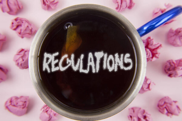 Conceptual hand writing showing Regulations. Business photo showcasing Rules Laws Corporate Standards Policies Security Statements written on Tea in Cup within Paper Balls on plain background.