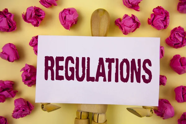Text sign showing Regulations. Conceptual photo Rules Laws Corporate Standards Policies Security Statements written on Sticky Note paper on plain background Paper Balls and Wooden Robot Toy.
