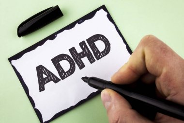 El yazısı metin DEHB. Kavram öğrenme anlamına gelir daha fazla zor bir görev üzerinde beyaz yapışkan not kağıdı Marker düz arka planda tutan adam tarafından yazılı öğretim çocuklar için kolaylaştırdı.