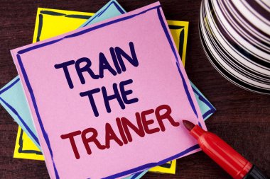 Word metin tren antrenör yazma. İş kavramı öğrenme tekniği öğretmenler kendileri üzerinde pembe bir yapışkan not kağıdına ahşap arka plan Kupası ve damgalı yanında yazılı olan öğrenciler için