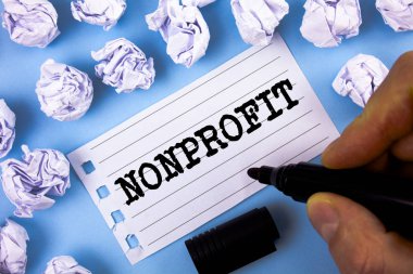 Word metin yazma Nonprofit. Not defteri kağıt üzerinde düz mavi arka plan kağıt topları yanındaki adam tarafından yazıldı executor için gelirleri elde edebilirim faaliyetleri için iş kavramı.