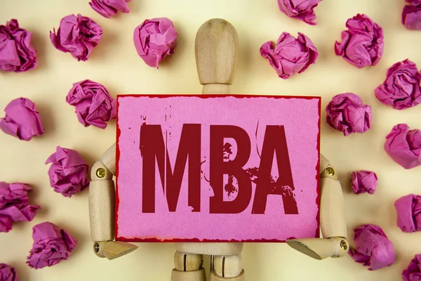 Handwriting text Mba. Concept meaning Master of Business Administration Advance Degree After College Studies written on Sticky Note paper holding by Wooden Robot Toy plain background Paper Balls.