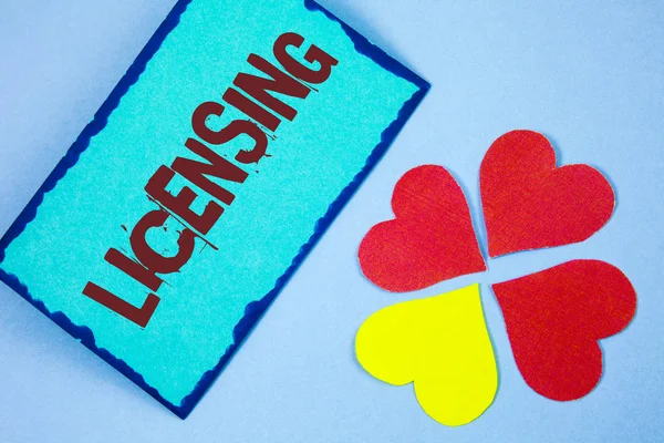 Signo de texto que muestra Licencias. Foto conceptual Conceder una licencia Legalmente permitir el uso de algo Permitir la actividad escrita en papel Sticky Note sobre fondo llano Papel Love Hearts junto a él . — Foto de Stock