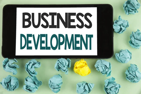 Conceptual hand writing showing Business Development. Business photo text Develop and Implement Organization Growth Opportunities written on Mobile Phone Screen on the plain background Paper Balls. — Stock Photo, Image