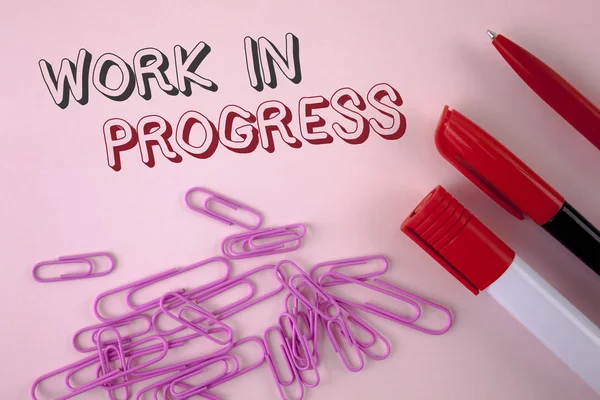 Writing note showing  Work In Progress. Business photo showcasing People is working right know to deliver expected results written on plain Pink background Pen Marker and Paper Pins next to it.
