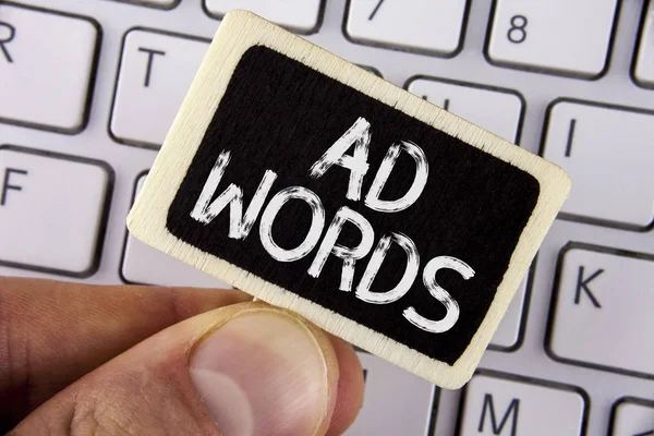 Writing note showing  Ad Words. Business photo showcasing Advertising a business over first of internet search results written on Wood Piece holding by man on the Laptop.