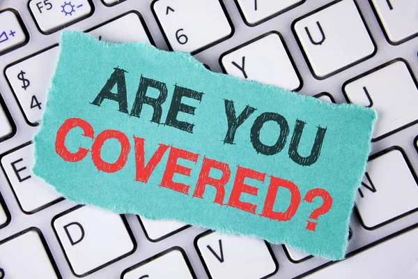 Handwriting text writing Are You Covered Question. Concept meaning asking about you insurance health statement written on tear Sticky Note Paper placed on the Laptop.