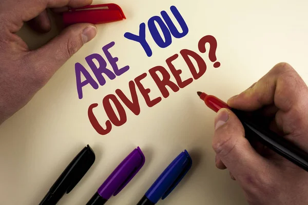 Text sign showing Are You Covered Question. Conceptual photo asking about you insurance health statement written by Man on plain background Markers next to it.