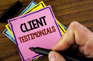 Metin Müşteri Testimonials yazmak kelime. Müşteri kişisel deneyimler değerlendirmeleri görüşleri pembe yapışkan not kağıt holding marker ahşap arka plan üzerinde adam tarafından yazılı görüşleri için iş kavramı 
