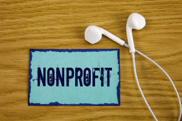 Writing note showing  Nonprofit. Business photo showcasing Activities that do not generate revenues to the executor written on Sticky Note Paper on wooden background Handsfree next to it.