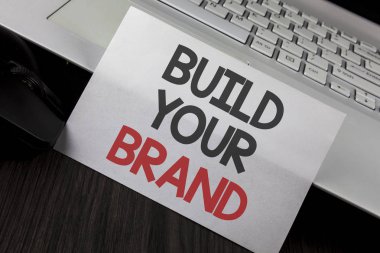 Build Your marka gösterilen not yazma. İş fotoğraf vitrine oluşturmak Model reklam E beyaz yapışkan not kağıdına yazılı pazarlama ahşap masa Laptop fare üzerinde yerleştirilen kendi logo sloganı