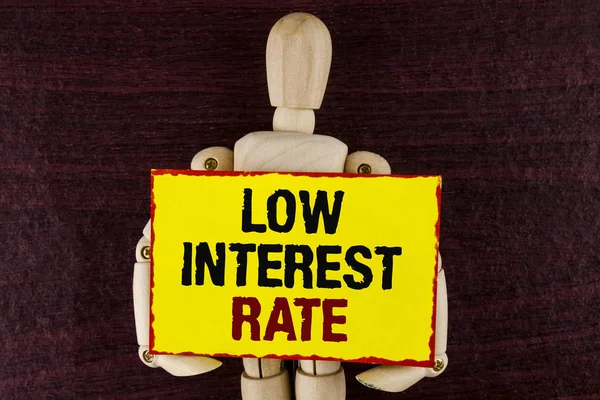 Word writing text Low Interest Rate. Business concept for Manage money wisely pay lesser rates save higher written on Sticky note paper holding by Wooden Robot Toy on wooden background.