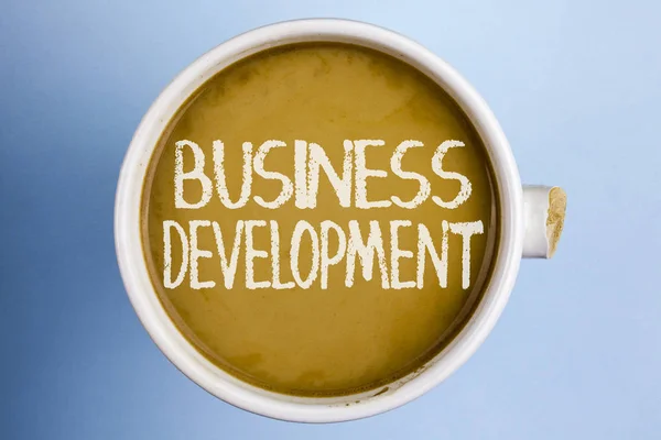 Text sign showing Business Development. Conceptual photo Develop and Implement Organization Growth Opportunities written on Coffee in a broken cup on the plain background. — Stock Photo, Image