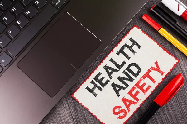 Handwriting text Health And Safety. Concept meaning being in good condition harmless Workouts Healthy food written on White Sticky Note Paper on the wooden background Laptop Pens next to it. — Stock Photo, Image