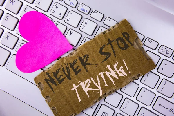 Word writing text Never Stop Trying Motivational Call. Business concept for go on do not give up Self confidence written on Tear Cardboard Piece placed on the Laptop Pink Heart next to it.