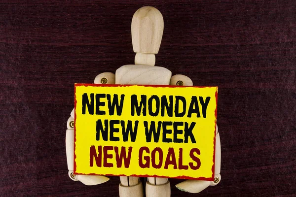 Word writing text New Monday New Week New Goals. Business concept for next week resolutions To do list Goals Targets written on Sticky note paper holding by Wooden Robot Toy on wooden background.