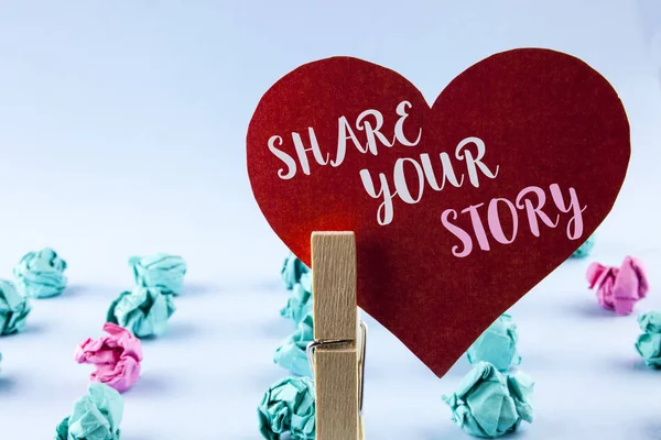 Handwriting text Share Your Story. Concept meaning Tell personal experiences talk about yourself Storytelling written on Red Paper Heart holding by Clip on plain background Paper Balls next to it.
