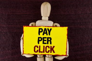 Word metin Pay Per Click yazma. İş kavramı reklamlar Reklam Seo pazarlama tutmak ahşap oyuncak tarafından eklemli ahşap arka plan üzerinde yapışkan not kağıt üzerinde yazılı ziyaretçilerden para almak için.