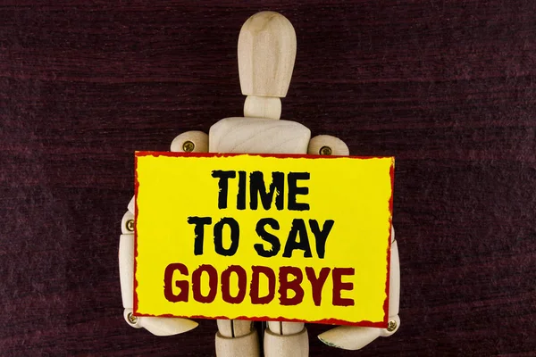 Word writing text Time To Say Goodbye. Business concept for Separation Moment Leaving Breakup Farewell Wishes Ending written on Sticky note paper holding by Wooden Robot Toy on wooden background.