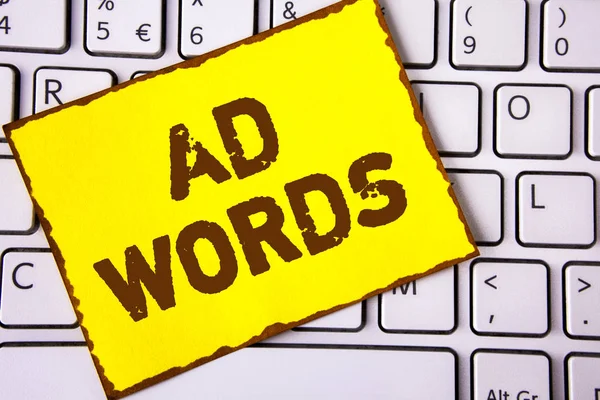 Text sign showing Ad Words. Conceptual photo Advertising a business over first of internet search results written on Yellow Sticky note paper placed on White keyboard. Top view.